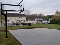 Completed reinforced concrete base, shown with hoop already installed, for green and grey backyard basketball court installation in Agawam, MA.