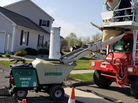 Background on the magic being done for basketball surface in Agawam, MA. Using a cart to drive small loads of cement to pour the court base, rather than heavy truck driving on lawn.