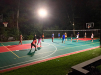 Large multicourt in use under the lights at night for a game of volleyball in Pembroke, MA.