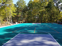 Almost completed emerald green and titanium residential basketball court, hoops, fence, secondary lines, portable net, and LED lighting for night play in Bolton, MA.