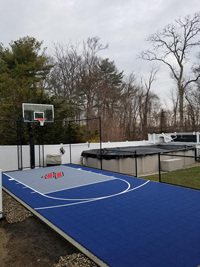 Small blue and grey backyard basketball court with custom H logo in Braintree, MA.