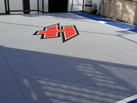 Closeup detail of custom red H logo on small blue and grey basketball court in Braintree, MA.