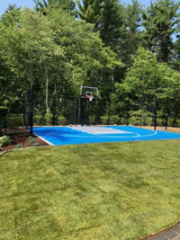 Blue and gray residential basketball court in Easton, MA, new sod lawn in foreground.