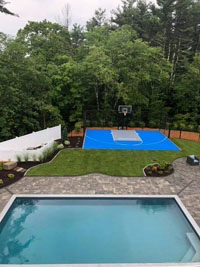 Blue and gray residential basketball court in Easton, MA, with pool in foreground.
