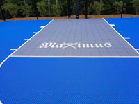Closeup of Maximus crossed swords logo on blue and gray residential basketball court in Easton, MA.