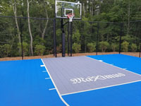 Kids shown on blue and gray residential basketball court in Easton, MA, with landscaping by Evergreen still in progress in foreground.