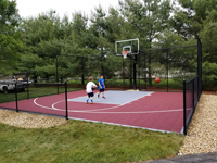 Kids using their new red and grey basketball court in Groton, MA.