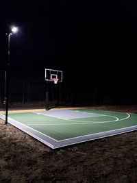 Backyard basketball court with lighting for night play and a batting cage in Hanover, MA.
