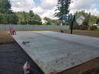 Partially completed construction of a basketball court featuring Celtics logo, with fire pit, patio, and light for night play, in Londonderry, NH.