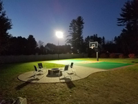 Basketball court featuring Celtics logo, with fire pit, patio, and light for night play, in Londonderry, NH.