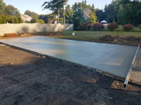 Drying con crete base for basketball court featuring Celtics logo, with fire pit, patio, and light for night play, in Londonderry, NH.