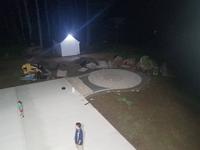 Night preview of incomplete basketball court featuring Celtics logo, with fire pit, patio, and light for night play, in Londonderry, NH.