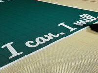Closeup of some of the custom text on a tan and green basketball court in Londonderry, NH.