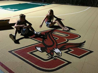 Closeup of kids posing with BC Eagles logo in corner of basketball court.