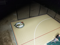 Custom logo under the lights on tan and green basketball court in Londonderry, NH.