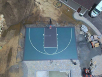 Green and black basketball court in Marion, MA, shown from above before landscape completion, courtesy of the owner's drone.