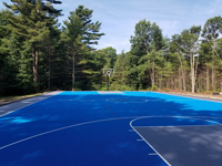 Large royal blue and titanium basketball court with golf seahorse logo at Bay Club in Mattapoisett, MA, as viewed from beneath hoop at one end, looking at the opposite end, showing the sheer size..