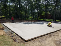 Smoothing cement underlay for graphite and orange residential basketball court replacing a dead pool in Walpole, MA.