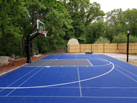 View from left end of completed installation of royal and charcoal backyard basketball in Ashland, MA.