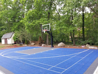 Right front angle view of most of royal blue and charcoal residential basketball court in Ashland, MA.