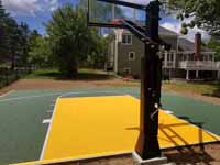 View from behind goal of olive green and yellow residential basketball court in Easton, MA.