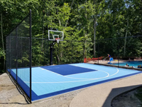 Light and royal blue basketball court installed beside existing pool in Medway, MA.