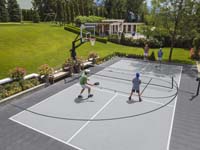 People enjoying pickleball on a charcoal and gray multicourt that also includes basketball.