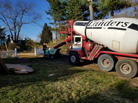 Cement mixer and small cart to transport batches to base form without truck needing to enter back yard during construction of dark green basketball court in Duxbury, MA.